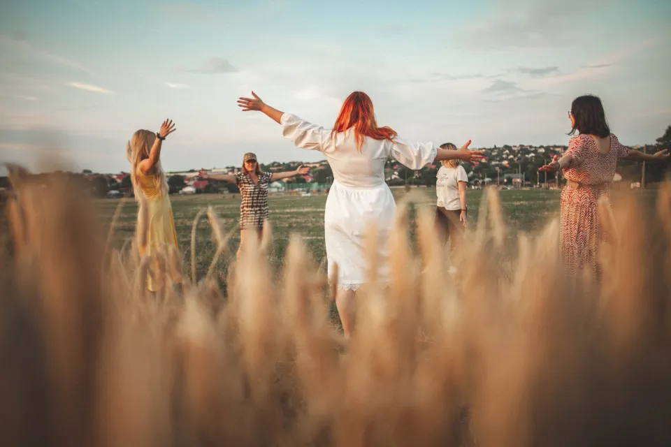 Participanți la un atelier Mișcare cu Sens, cu brațele deschise, într-un câmp